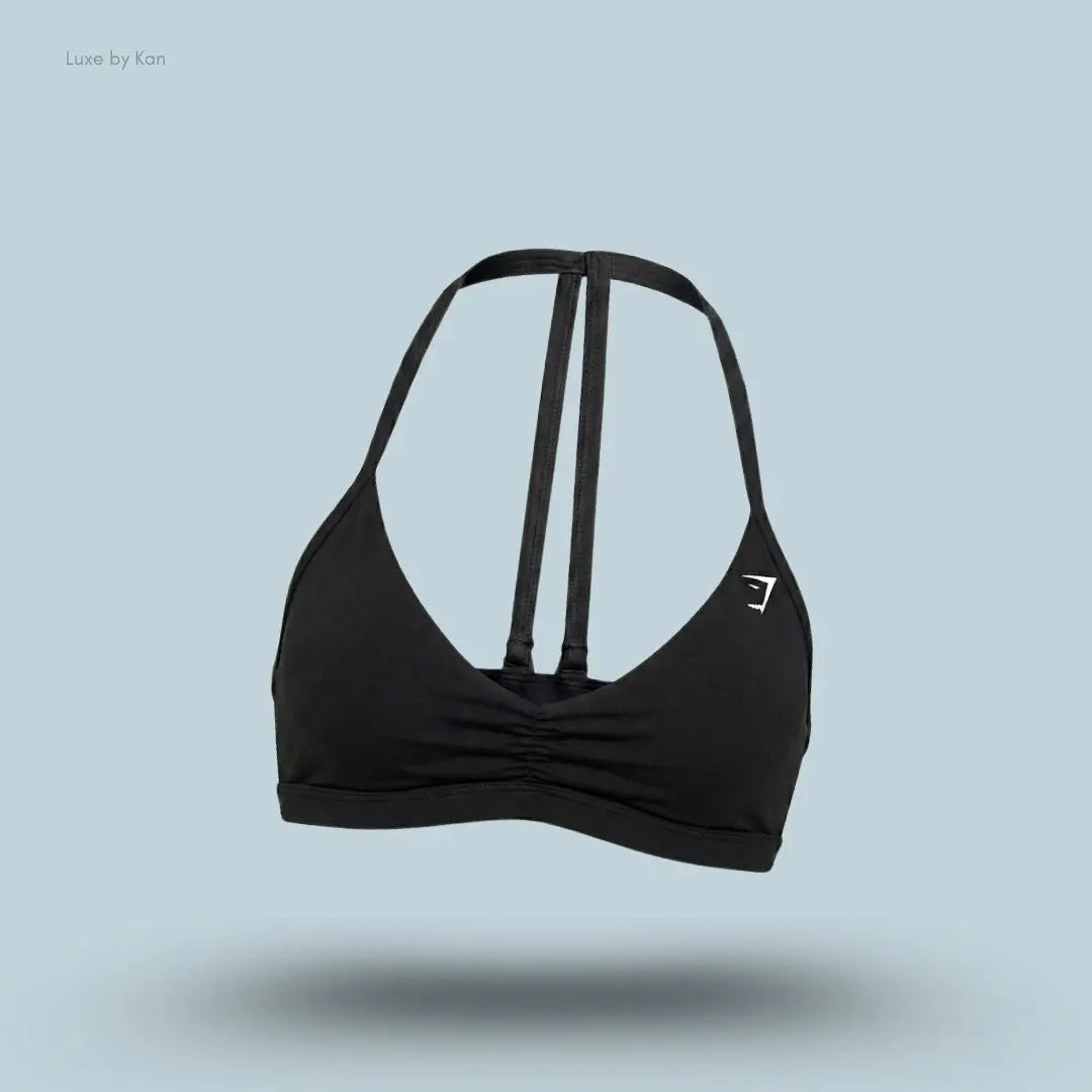 Gymshark Minimal Sports Bra 2.0 in Black, flat lay on light blue background