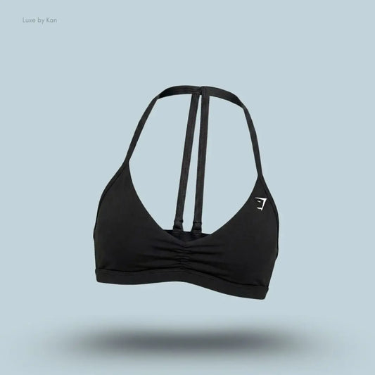 Gymshark Minimal Sports Bra 2.0 in Black, flat lay on light blue background