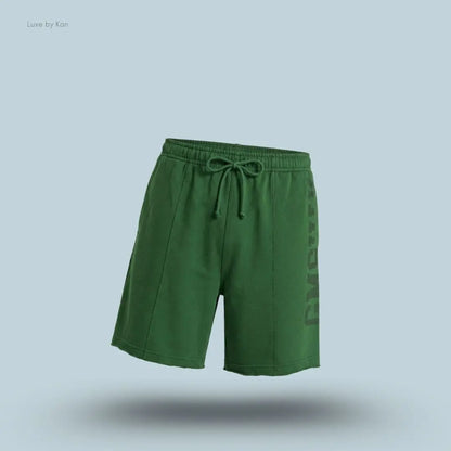 Gymshark Accent Graphic Sweat Shorts in green displayed on a blue background with an oversized fit and raw hem design
