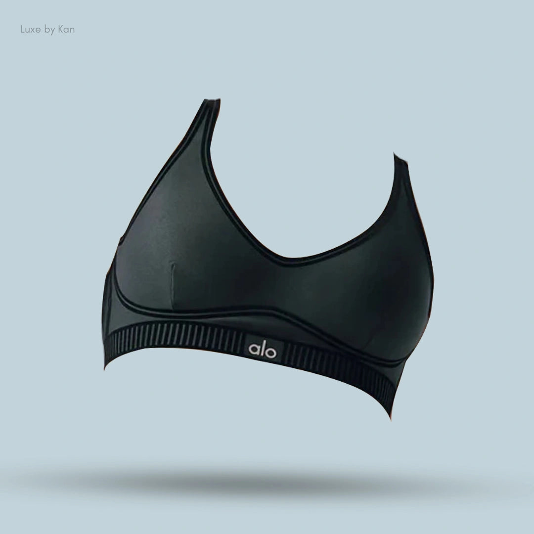 Alo Airlift Line Up Bra in black, flat lay on light blue background