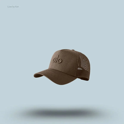 Alo District Trucker Hat in Espresso, flat lay on light blue background