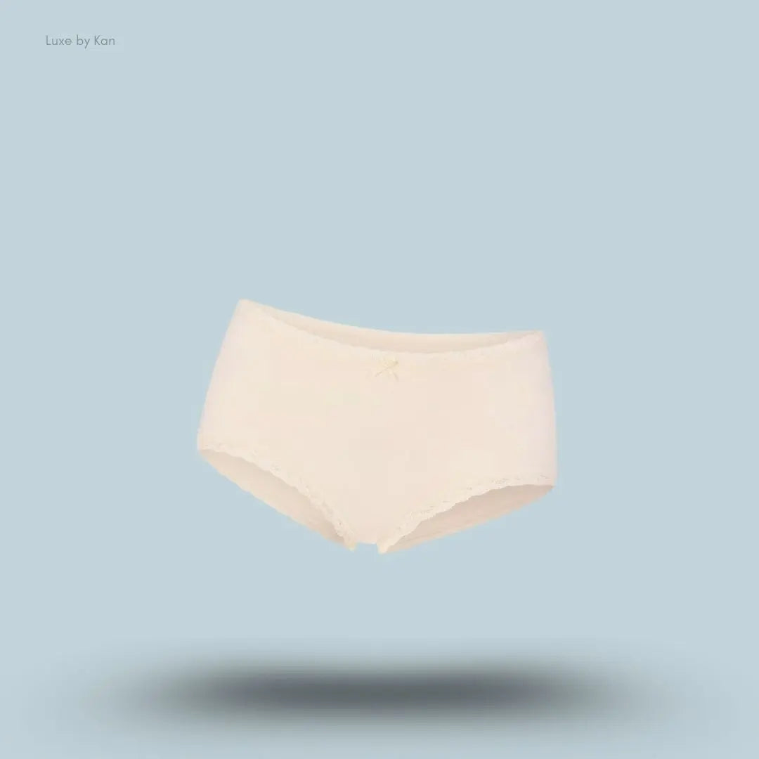 SKIMS Lightweight Cotton Lace Boy Short in Butter Tonal, flat lay on light blue background