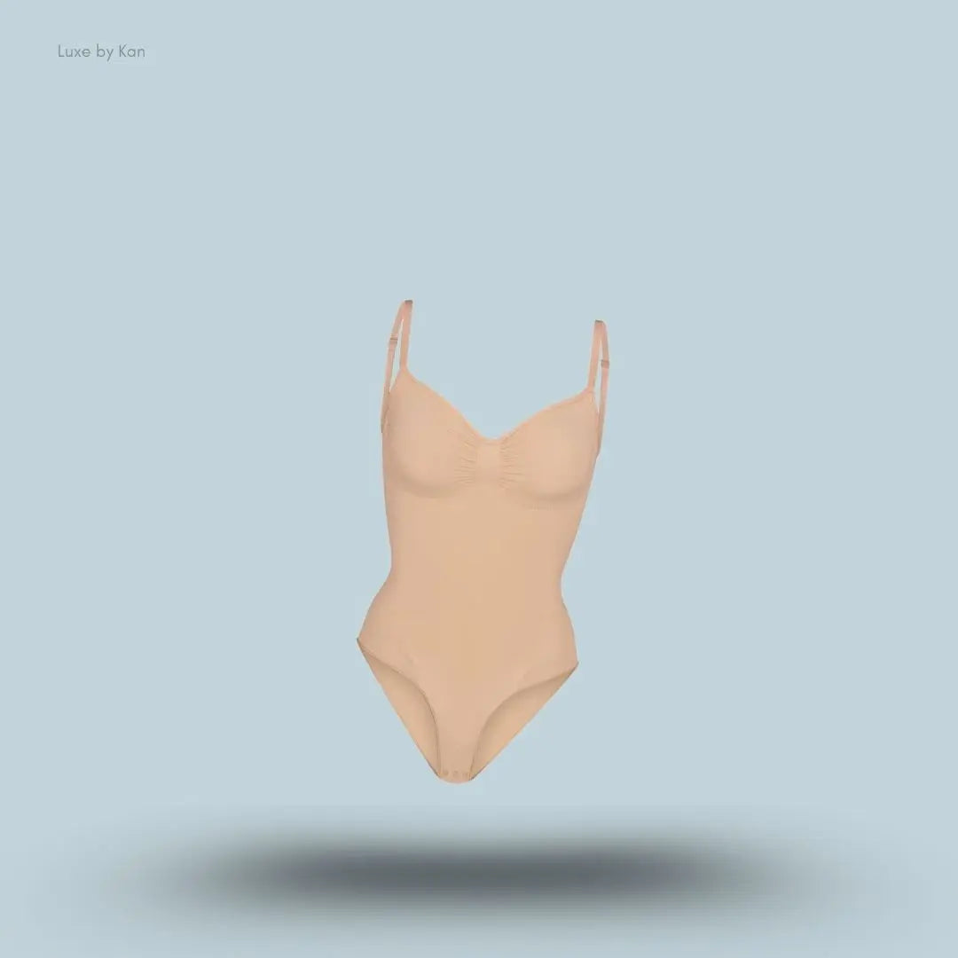 SKIMS Seamless Sculpt Brief Bodysuit in a nude shade, front view with adjustable shoulder straps and seamless sculpting design on blue background