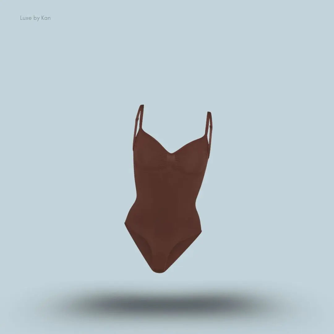 SKIMS Seamless Sculpt Brief Bodysuit in a dark brown shade, front view with adjustable shoulder straps and seamless sculpting design on blue background