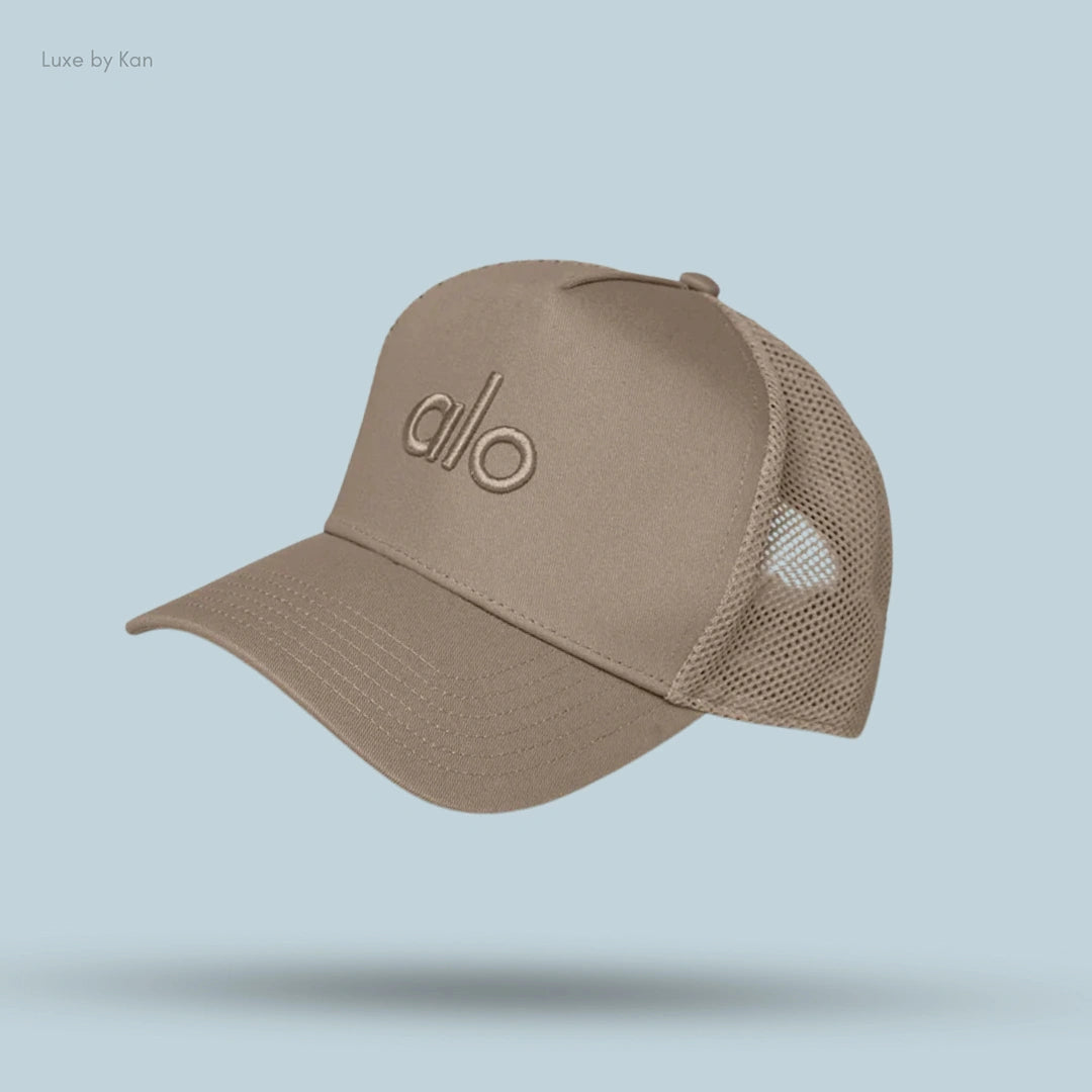 Alo District Trucker Hat in Gravel, flat lay on light blue background