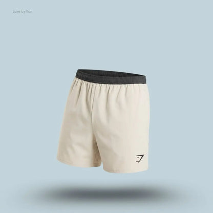 Gymshark Arrival Contrast Shorts in light beige displayed on a blue background with a slim-fit athletic shorts design
