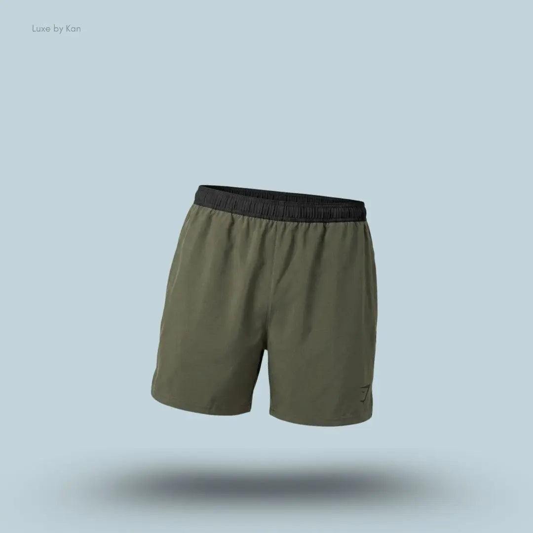 Gymshark Arrival Contrast Shorts in olive green displayed on a blue background with a slim-fit athletic shorts design
