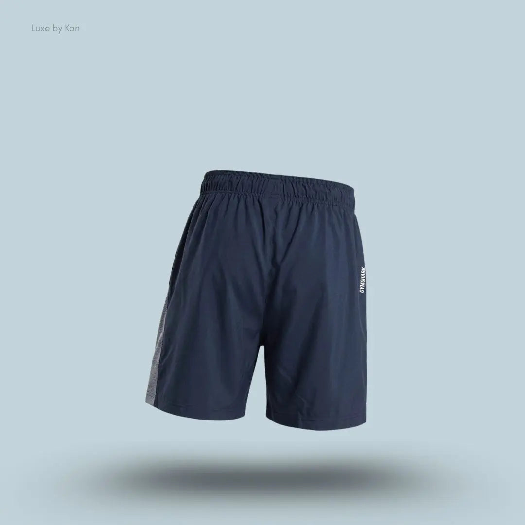 Gymshark Sport 7" Shorts in dark blue with contrast side panels on a blue background back view