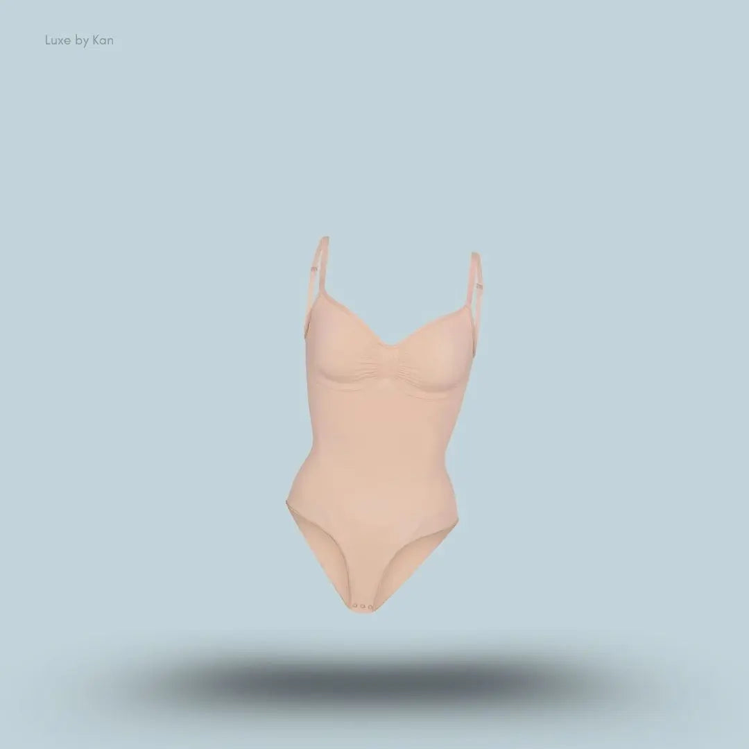SKIMS Seamless Sculpt Brief Bodysuit in a nude shade, front view with adjustable shoulder straps and seamless sculpting design on blue background