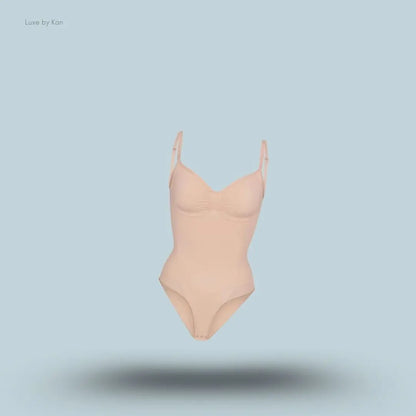 SKIMS Seamless Sculpt Brief Bodysuit in a nude shade, front view with adjustable shoulder straps and seamless sculpting design on blue background