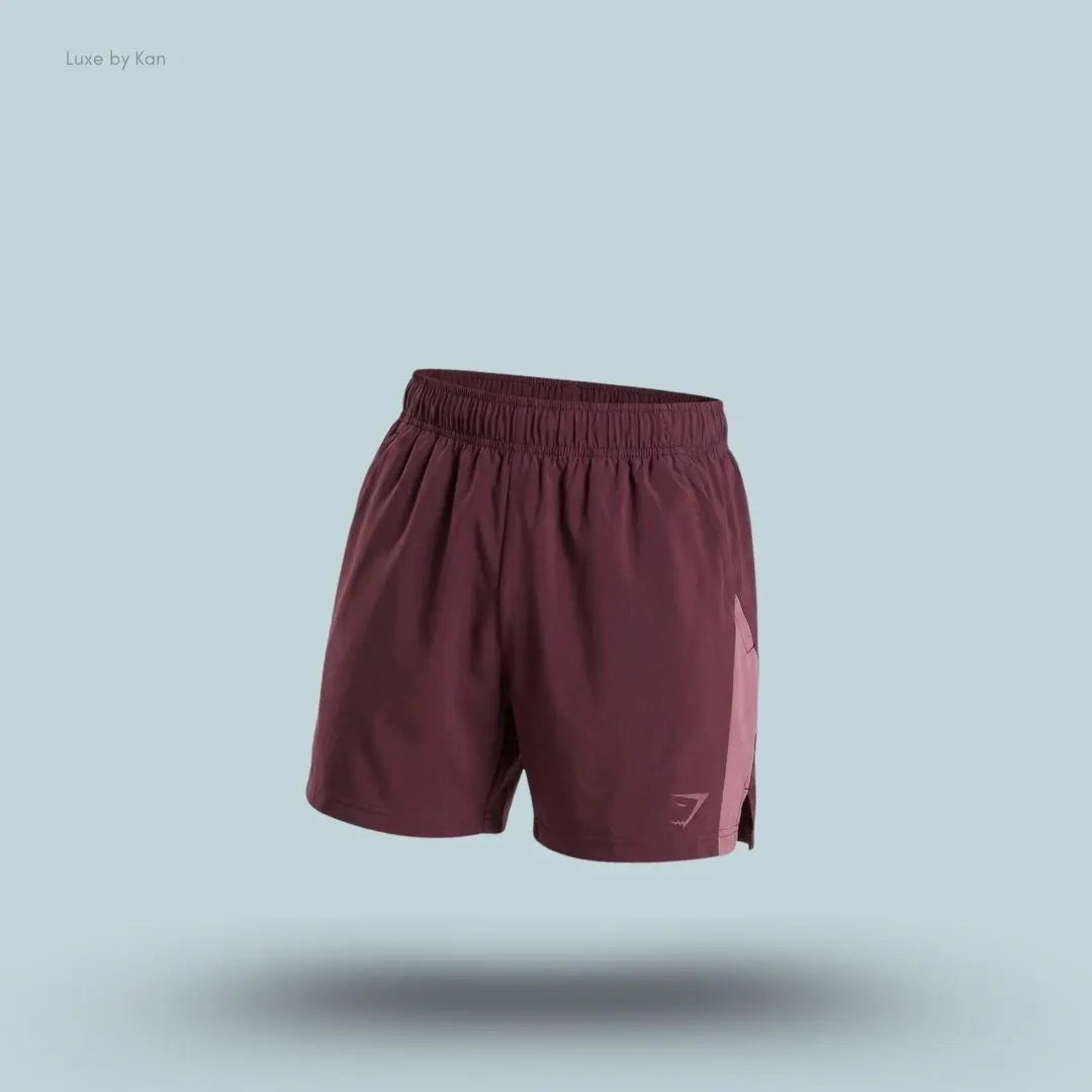 Gymshark Sport 5" Shorts men's slim-fit training shorts in burgundy with contrast side panels on a blue background