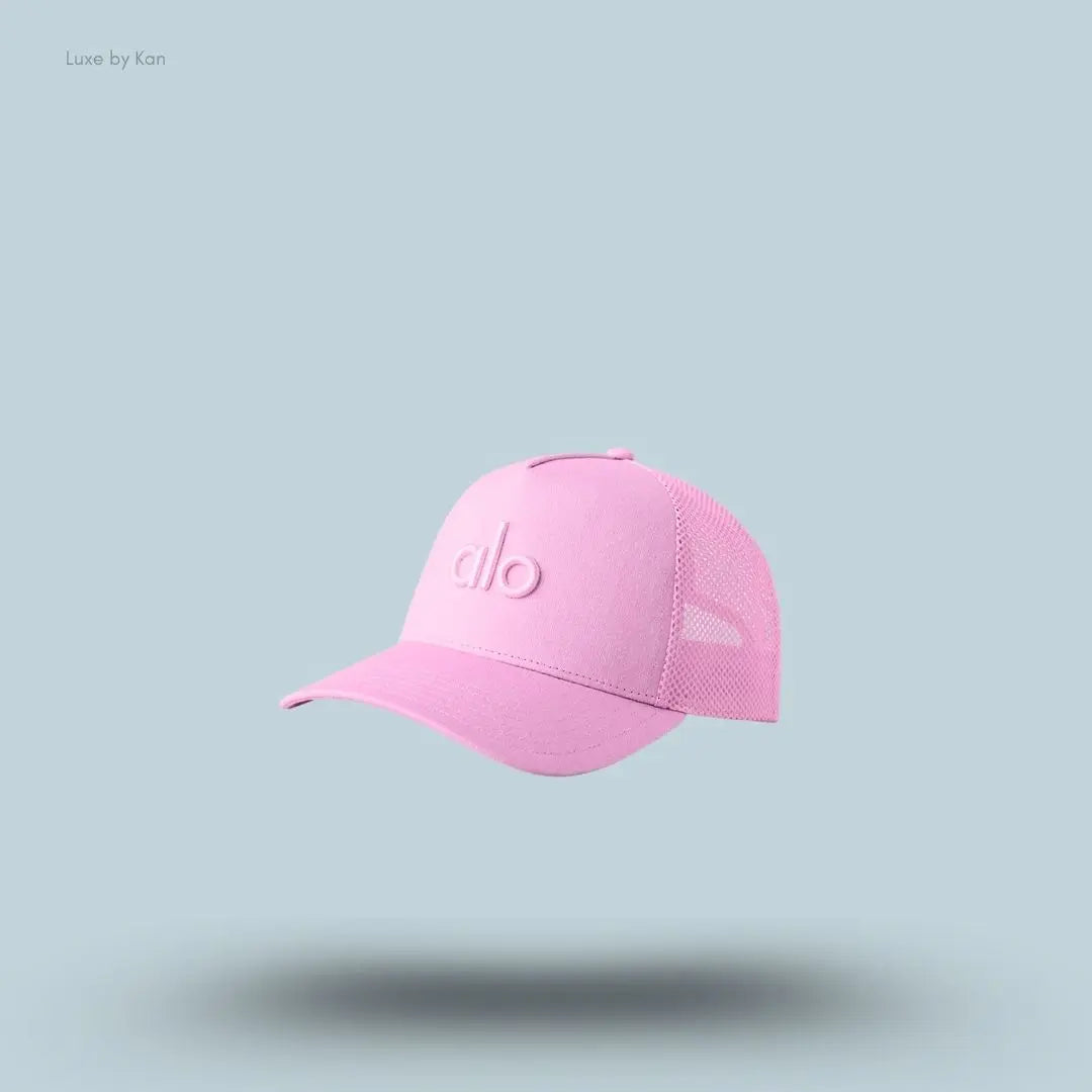 Alo District Trucker Hat in Candy Heart Pink, flat lay on light blue background