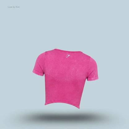 Gymshark x Bratz Crop Top in pink  displayed on a blue background with a body-fit cropped design with back view