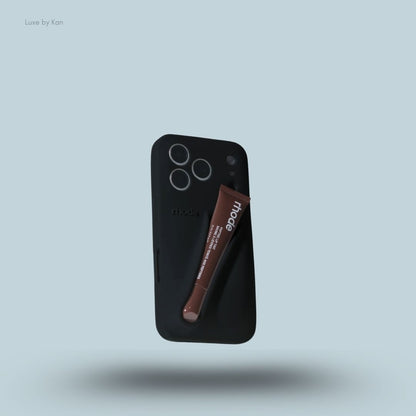 Rhode phone case in black against blue background; the word "rhode" embossed on the back, with loop for lip balm.