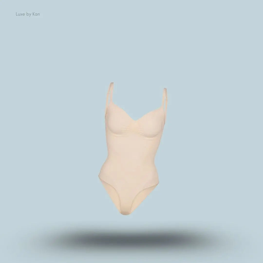 SKIMS Seamless Sculpt Brief Bodysuit in a nude shade, front view with adjustable shoulder straps and seamless sculpting design on blue background