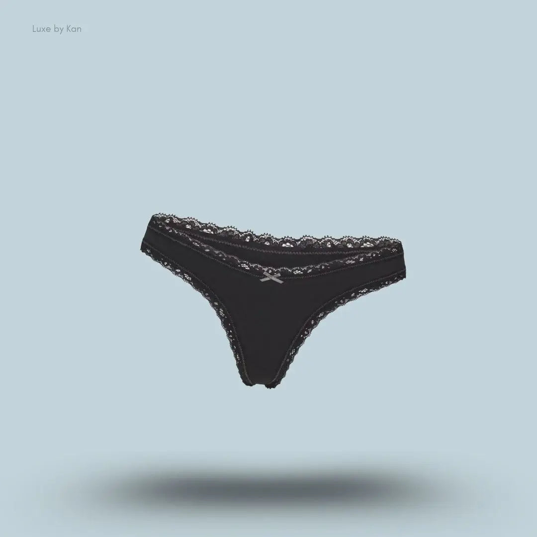 SKIMS Lightweight Cotton Lace Thong in Soot, flat lay on light blue background