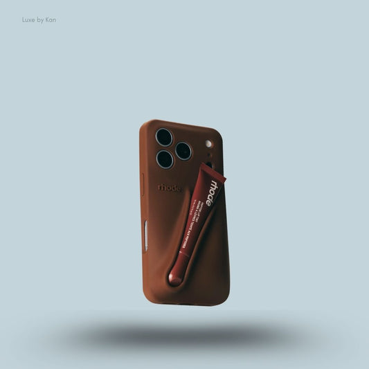 Rhode phone case in bronze against blue background; the word "rhode" embossed on the back, with loop for lip balm.