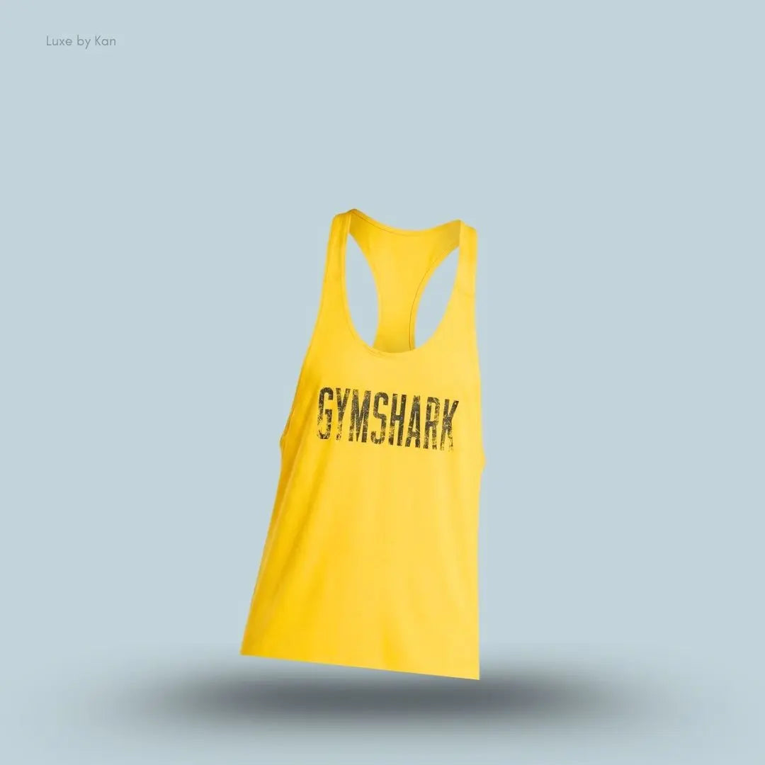 gymshark Accent Tank in yellow with a racerback design, faded front Gymshark graphic and slim-fit sleeveless training tank displayed on blue background