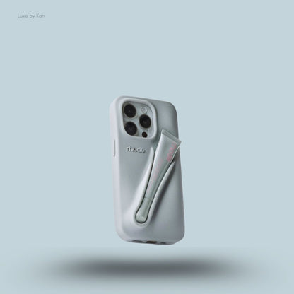Rhode phone case in grey against blue background; the word "rhode" embossed on the back, with loop for lip balm.