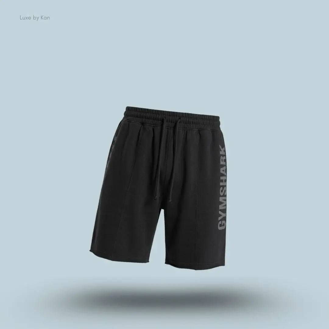 Gymshark Accent Graphic Sweat Shorts in black displayed on a blue background with an oversized fit and raw hem design