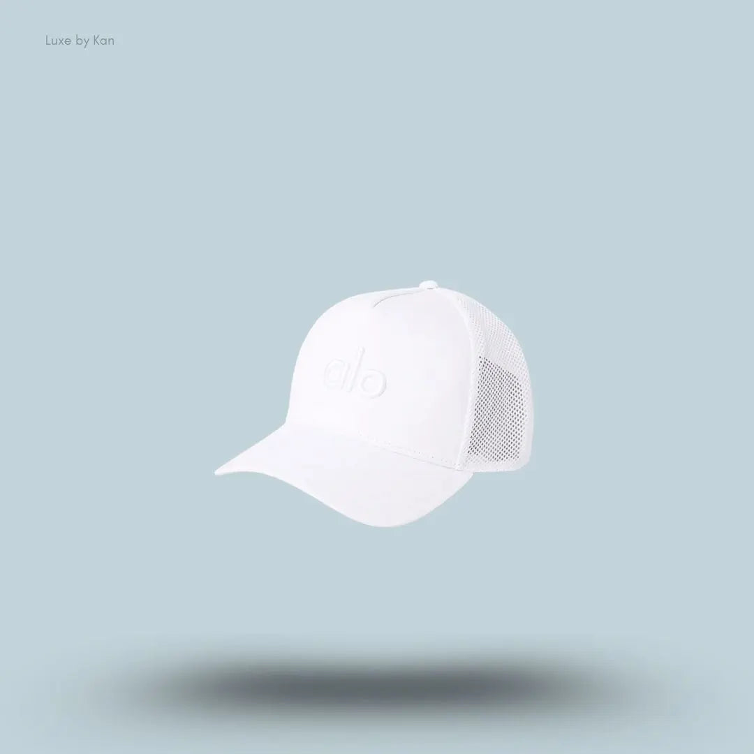 Alo District Trucker Hat in White, flat lay on light blue background